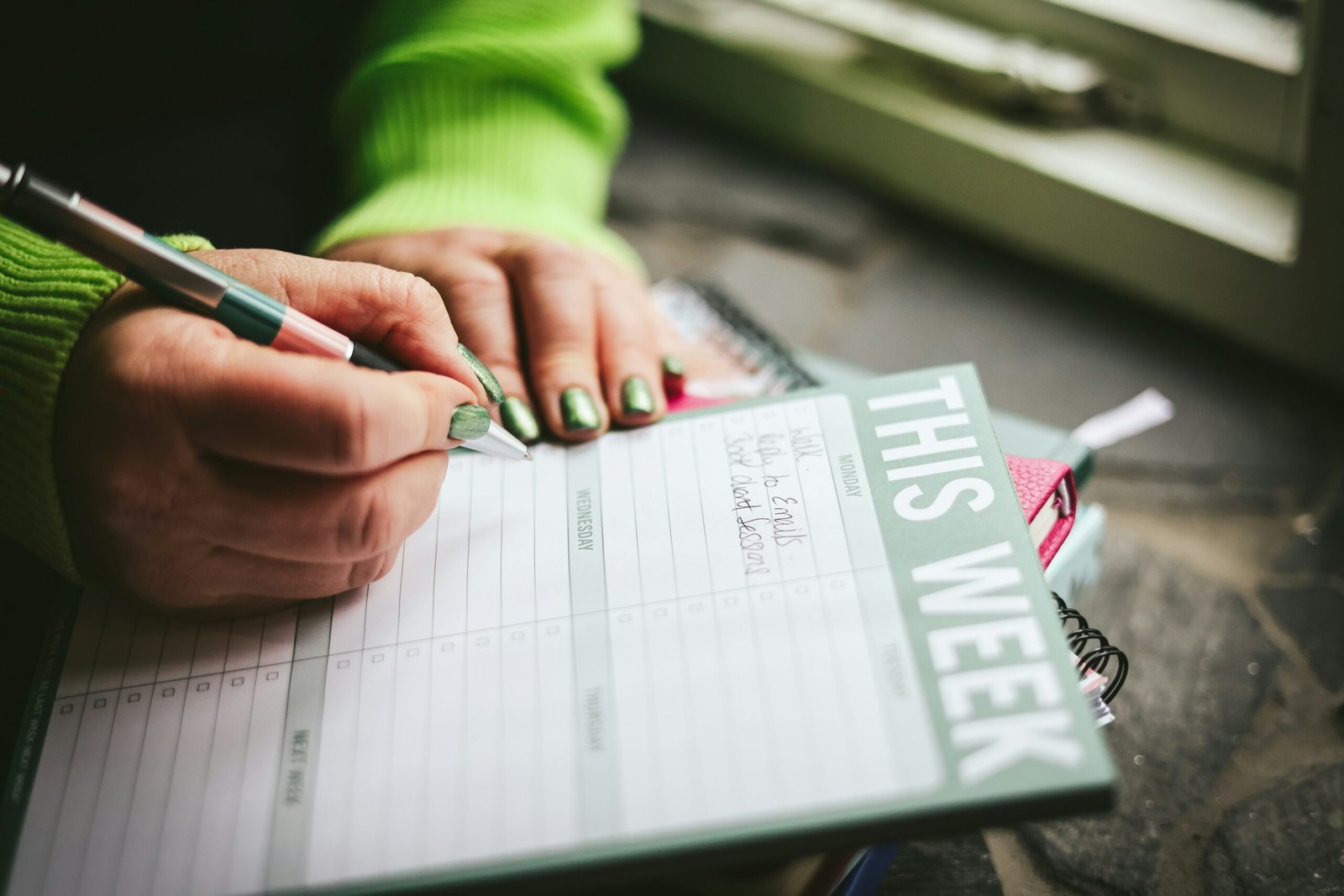 Hands writing in a weekly planner