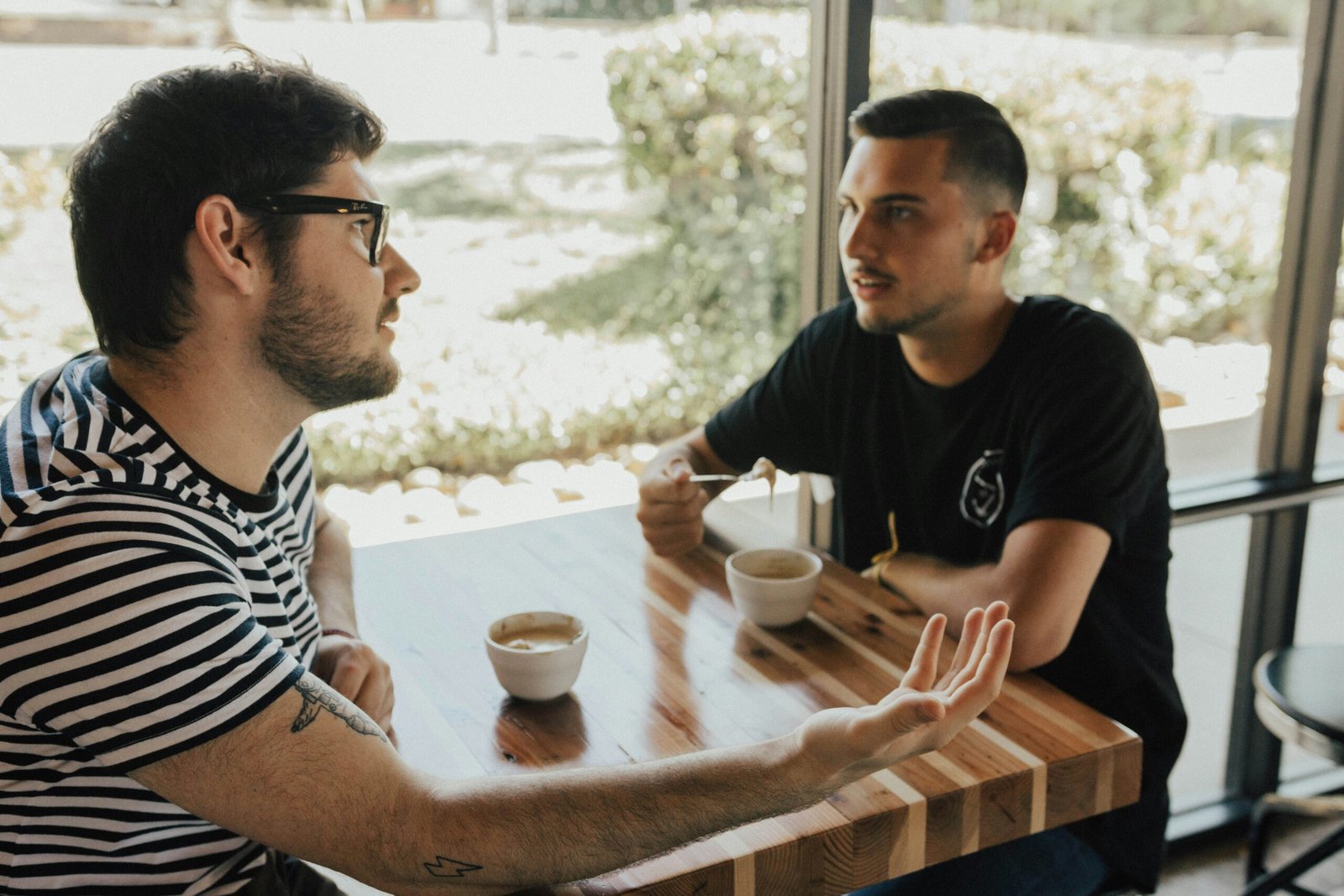 Two colleagues chatting over coffee at a cafe table