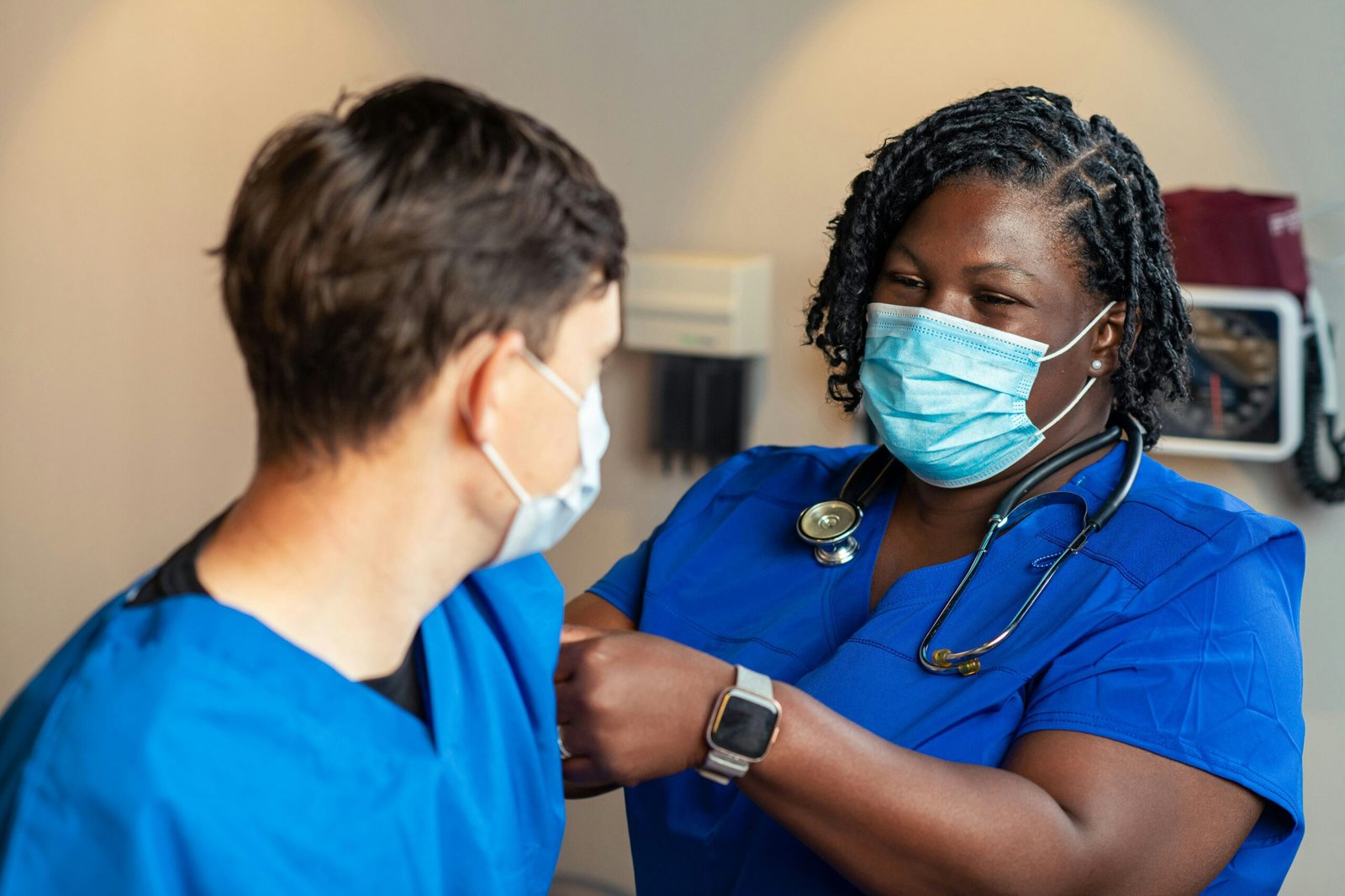 Two nurses in scrubs sharing a fist bump on a hospital ward