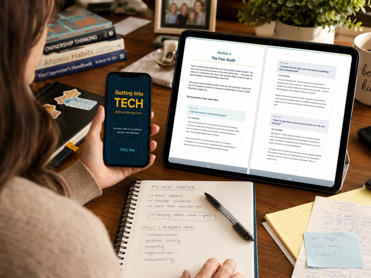 A woman reading the ebook on a phone and the workbook on a tablet while making notes