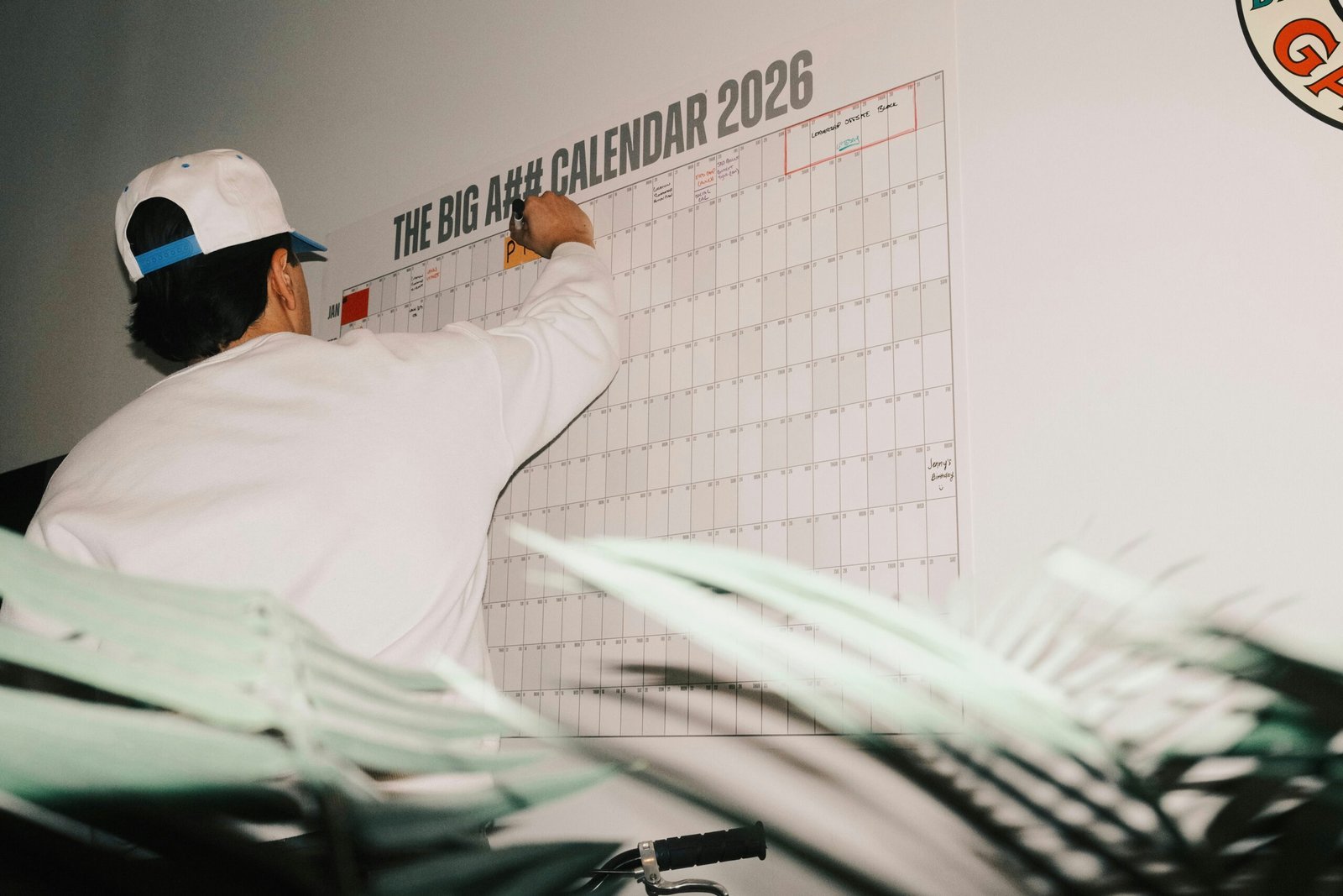 Person writing on a large wall calendar planner