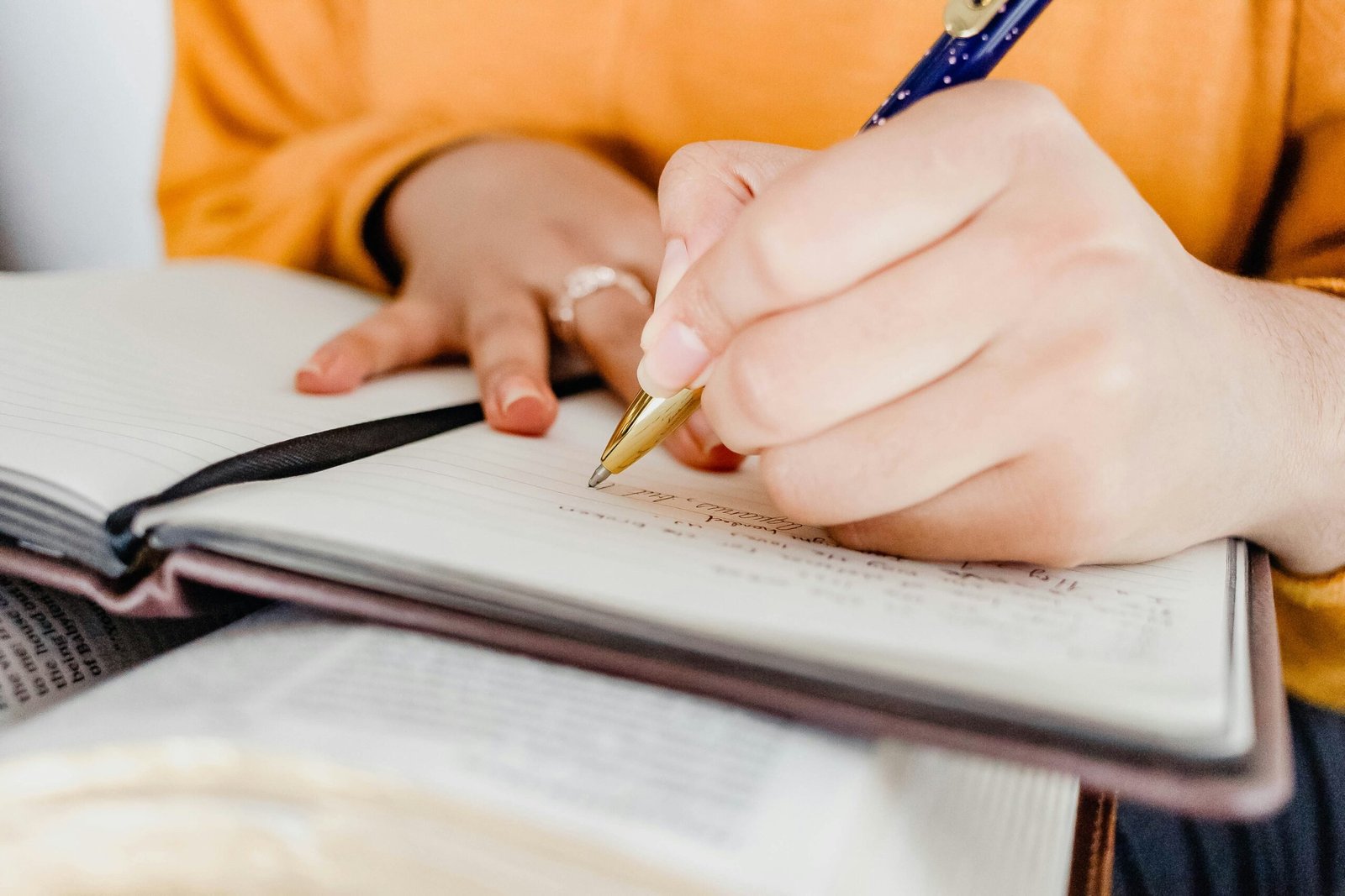 Close-up of hands writing notes by hand in an open notebook
