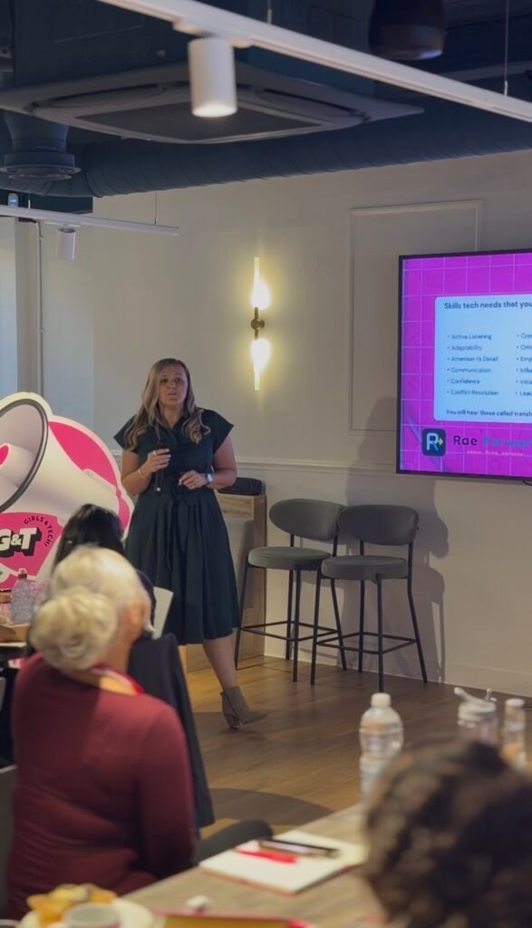 Holly Rae standing and holding a microphone while speaking at the Girls and Tech of Tomorrow Career Lab